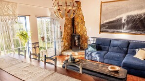 Una sala de estar moderna con chimenea de piedra, sofá azul y comedor con mesa larga y sillas.
