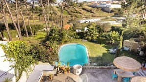 Un área de piscina en la azotea con sillones, una chimenea y sombrillas.