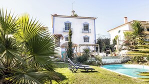 Un edificio blanco con detalles azules, piscina y palmeras.