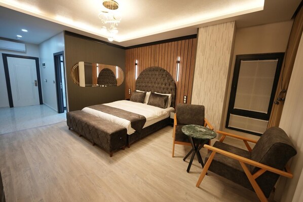 A modern bedroom with a large bed, a small round table, and a chair.