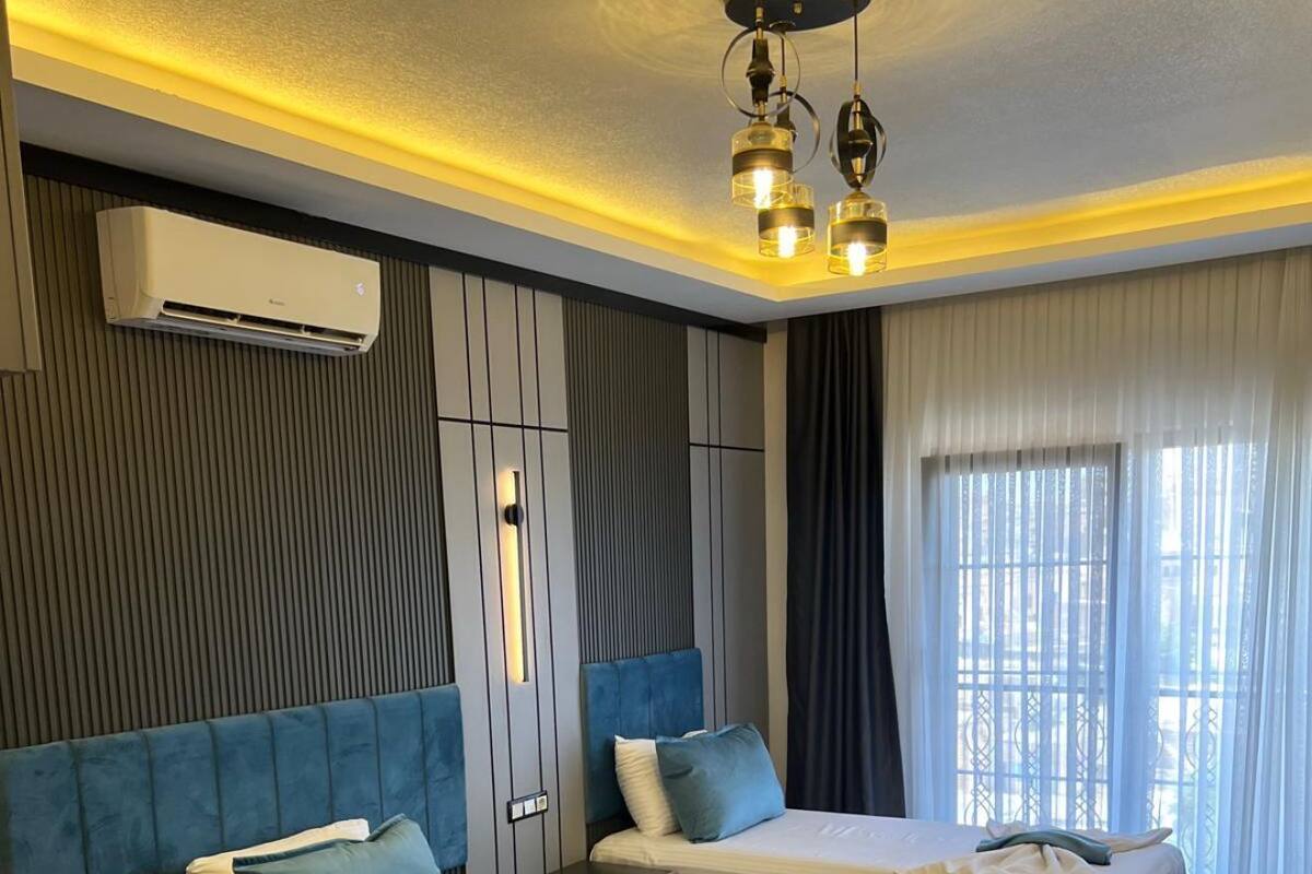 Una moderna camera d'albergo con due letti, un tavolo con piano in marmo e un lampadario.