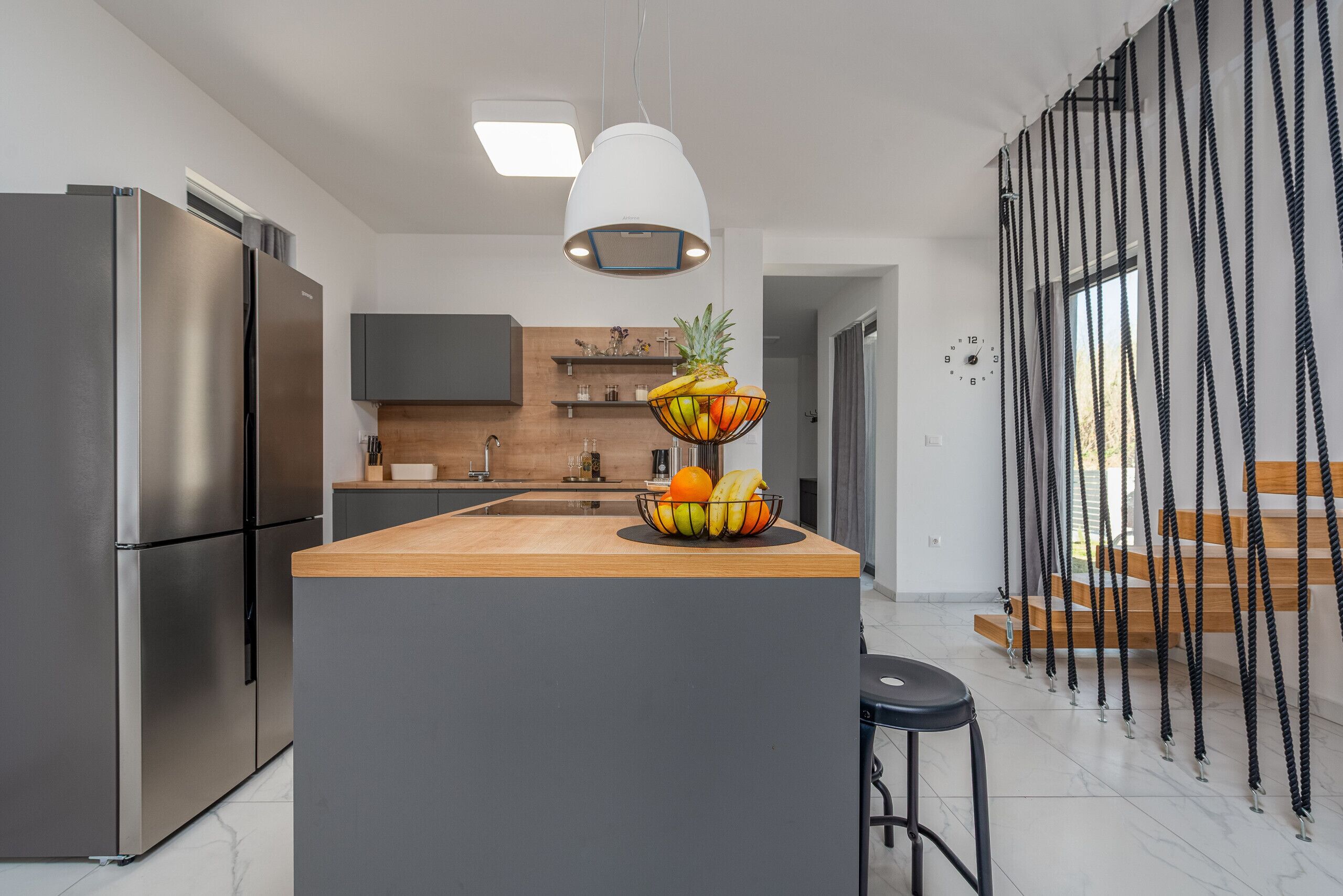 A modern kitchen with a central island, stainless steel appliances, and a fruit bowl.