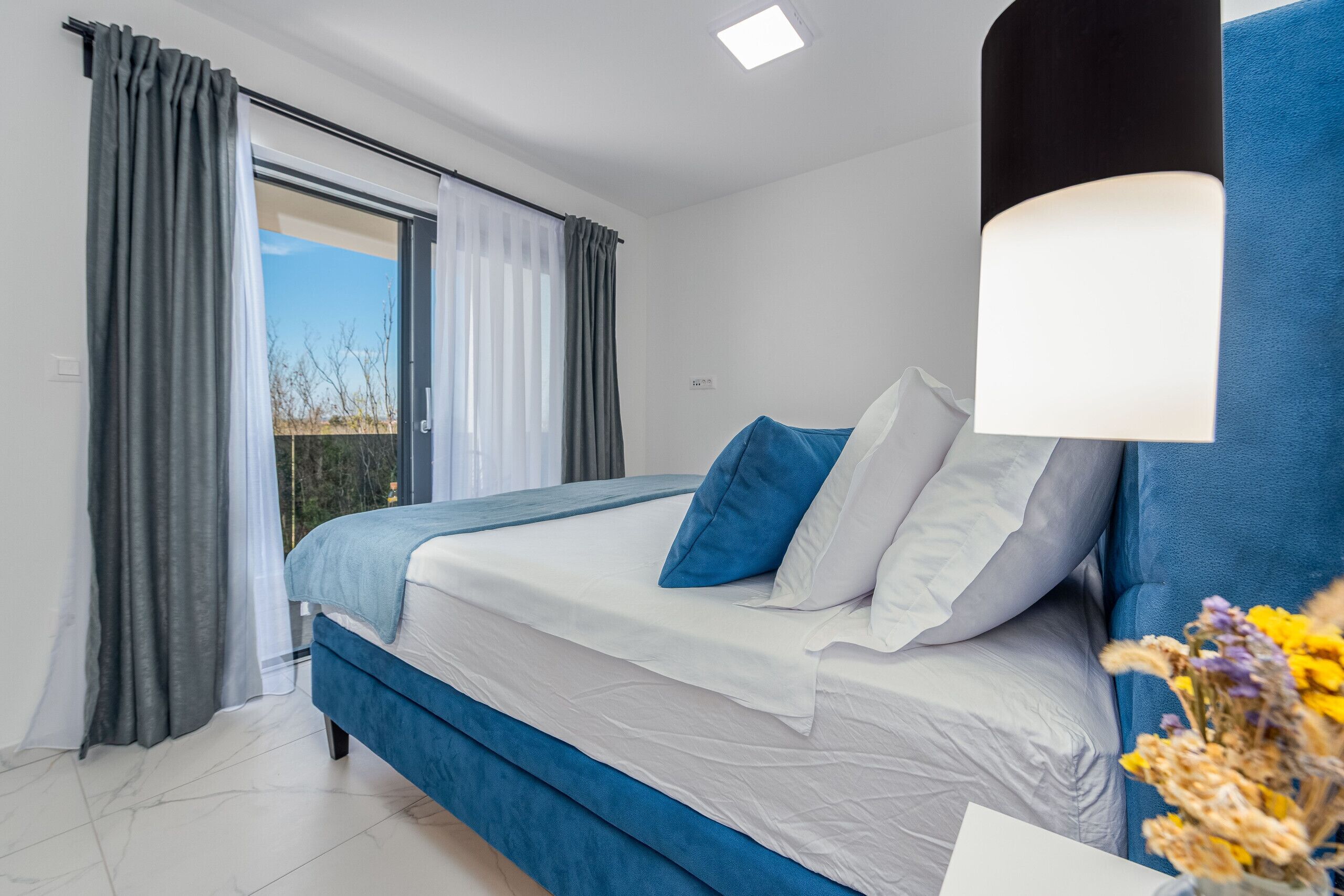 A bedroom with a bed, curtains, a window, and a lamp.