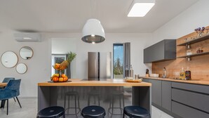 A modern kitchen with a central island, bar stools, and a large window. - Villa Merci Zadar Villas (Privlaka)