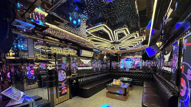 A karaoke room with neon lights, a stage, and a seating area. - Paloma Hotel (Van Don)