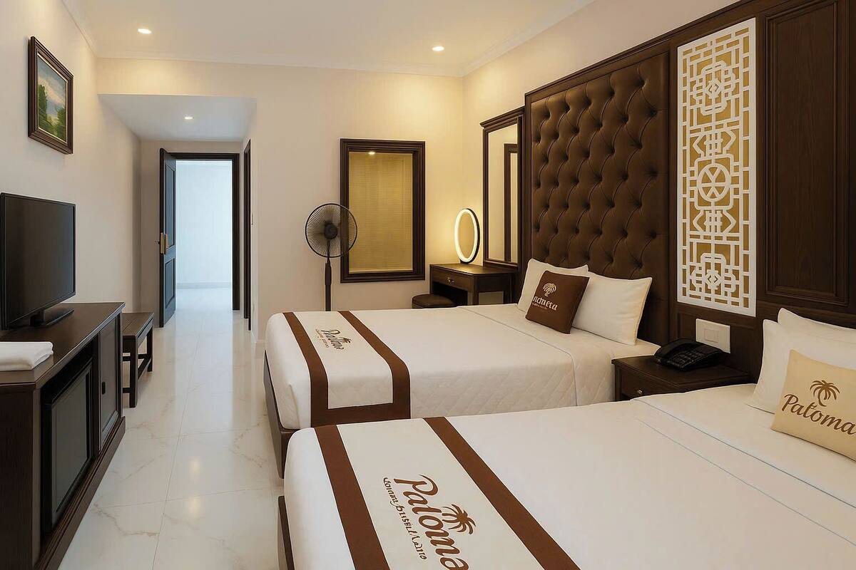 A hotel room with two beds, a TV, a desk, and a mirror.