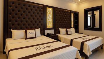 Quarto de hotel com duas camas, cada uma com encosto e colcha bordada com a inscrição 'Paloma'.