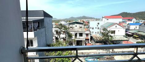 A balcony with a metal railing overlooking a residential area with various buildings and a clear sky.