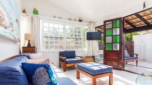Een kamer met een bank, stoelen, een tafel en een televisie.