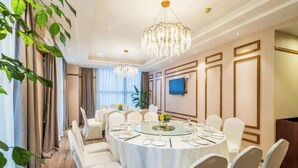 Un salón de conferencias con mesas redondas, sillas blancas y una araña de cristal.