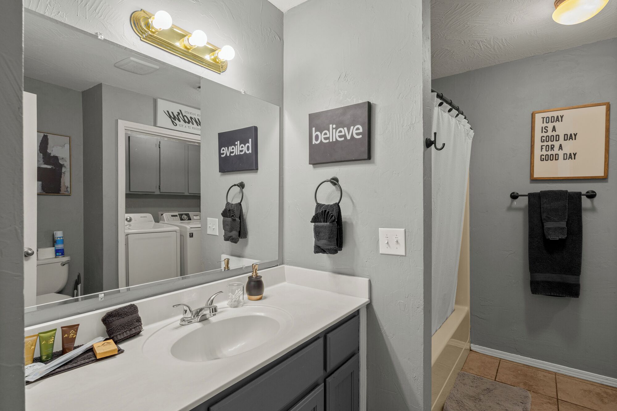 Un baño moderno con un espejo grande, tocador y zona de ducha.