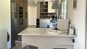 Una cocina moderna con una isla central, taburetes de bar y vistas al comedor.