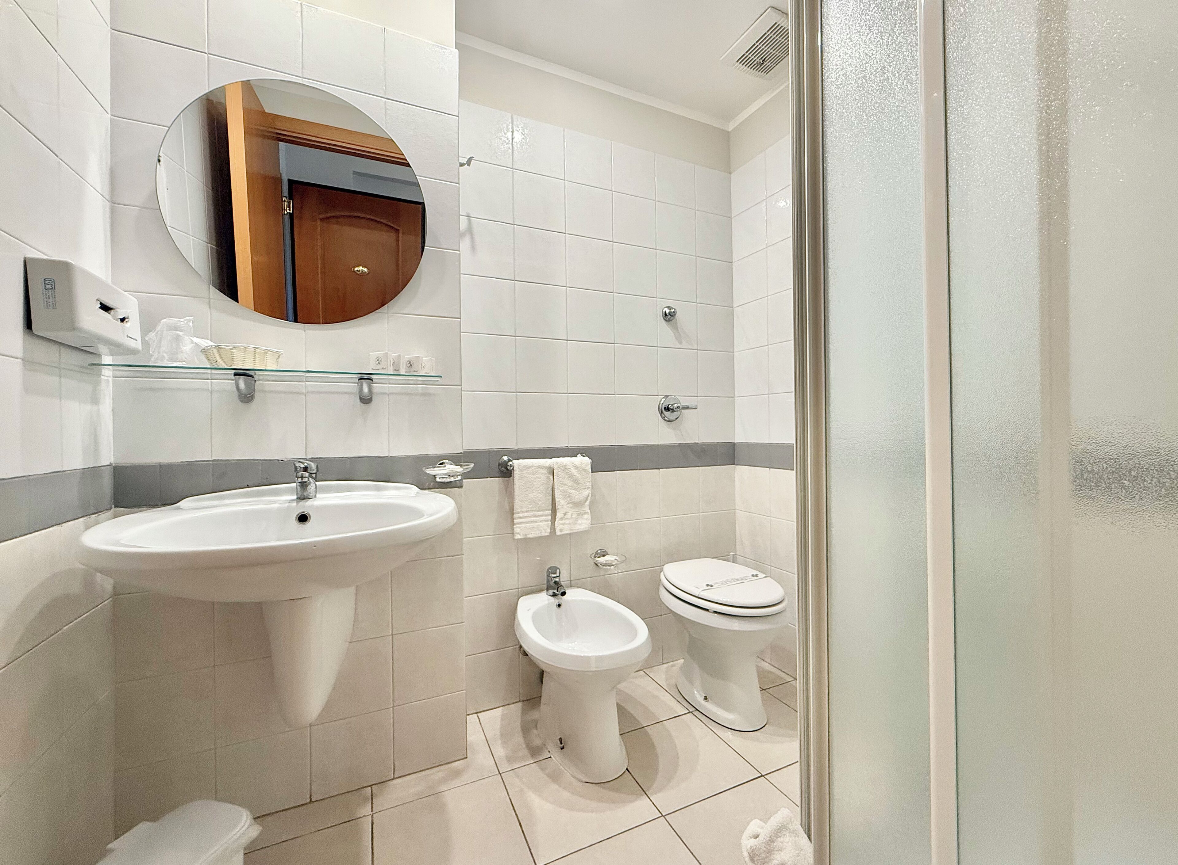 Une salle de bain équipée d’un lavabo, d’un bidet, de toilettes et d’une douche à parois en verre.