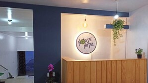 Ein Empfangsbereich mit einem Schild, das "Norte Hotel" zeigt, einer hängenden Pflanze und einem Blumentopf auf dem Schreibtisch.