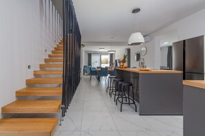 Μια σύγχρονη κουζίνα με ξύλινη σκάλα, ένα μπαρ και έναν χώρο τραπεζαρίας.