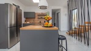 Una cocina moderna con una isla central, electrodomésticos de acero inoxidable y un frutero.