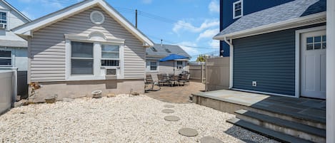 A residential property with a patio, outdoor seating, and a gravel driveway.