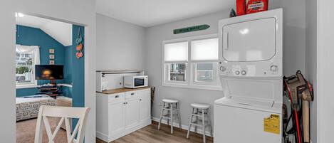 A compact kitchen with white cabinets, a microwave, and a washing machine.