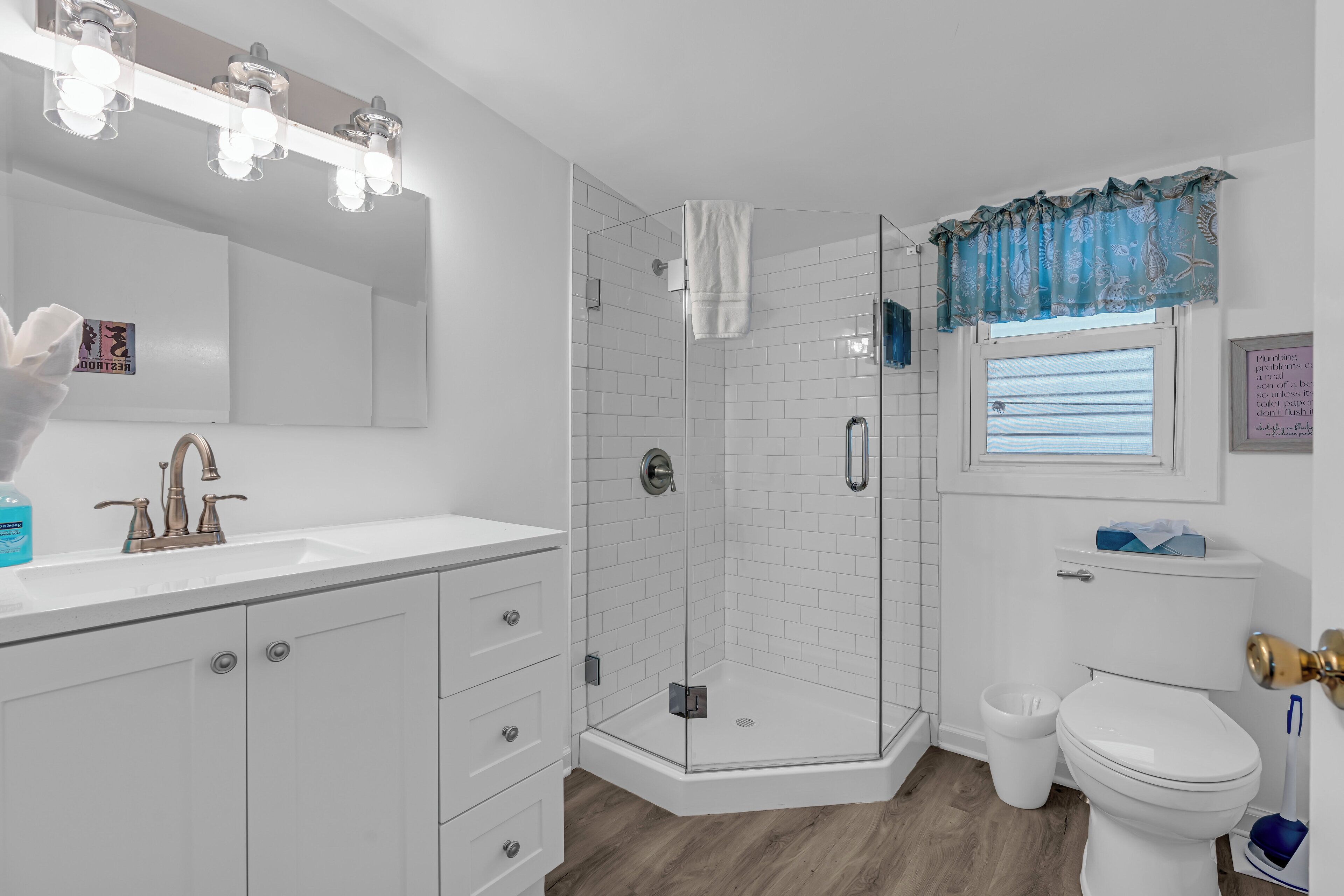 A modern bathroom with a glass-enclosed shower, white tiles, a sink with a faucet, and a toilet.