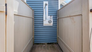 A narrow wooden pathway leading to a blue exterior wall with a showerhead mounted on it. - Coffee | BBQ Grill | Outdoor Dining | Wifi (Belmar)