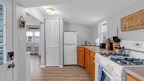 A modern kitchen with white cabinets, a gas stove, and a refrigerator. - Coffee | BBQ Grill | Outdoor Dining | Wifi (Belmar)