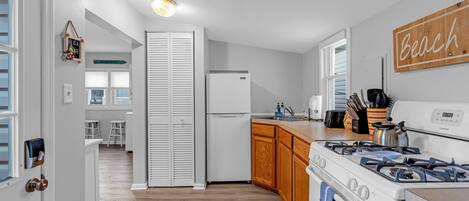 A modern kitchen with white cabinets, a gas stove, and a refrigerator.