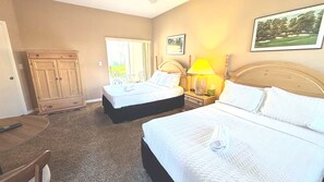 A hotel room with two beds, a desk, a chair, a wardrobe, and a window.
