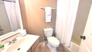 A bathroom with a sink, toilet, and shower curtain.