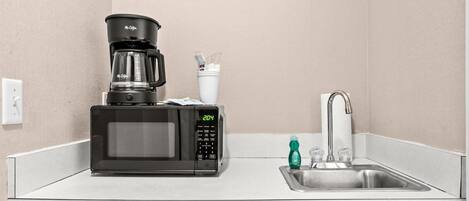A compact kitchenette with a coffee maker, microwave, and sink.