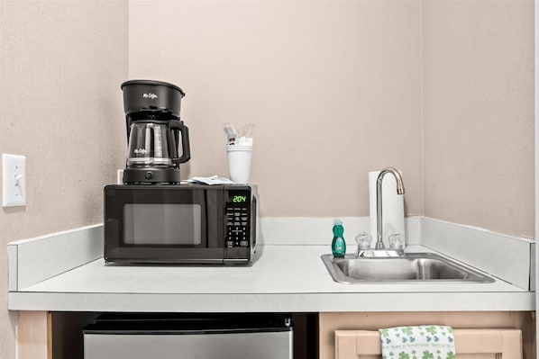 A compact kitchenette with a coffee maker, microwave, and sink.
