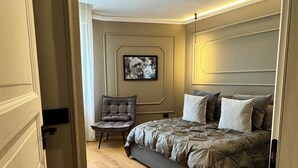 A bedroom with a bed, a chair, a painting on the wall, and a door. - Mentore Maison Prestige  (Noceto)