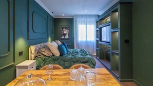 A bedroom with a green bedspread, a wooden table with glass decanters, and a nightstand. - Mentore Maison Prestige  (Noceto)