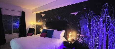 A modern bedroom with a large bed, a wall-mounted TV, and ambient lighting.