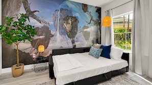 A modern bedroom with a large abstract painting, a bed with white bedding, a potted plant, and a side table with a lamp. - Lake Buena Vista Vacation Rental (Orlando)