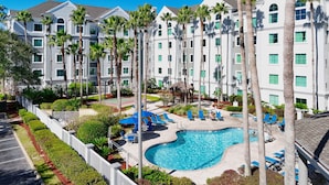 A resort with a swimming pool surrounded by palm trees and blue lounge chairs. - Lake Buena Vista Vacation Rental (Orlando)
