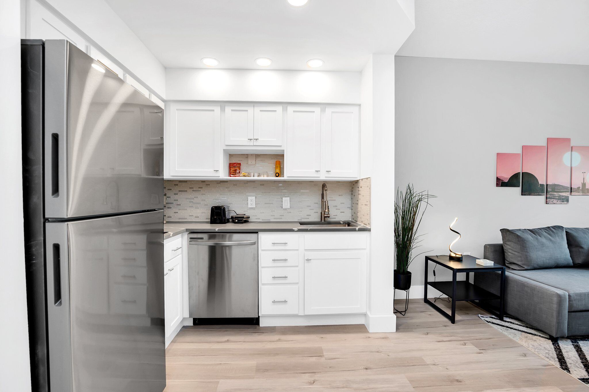 Una cocina moderna con armarios blancos, electrodomésticos de acero inoxidable y lavavajillas.