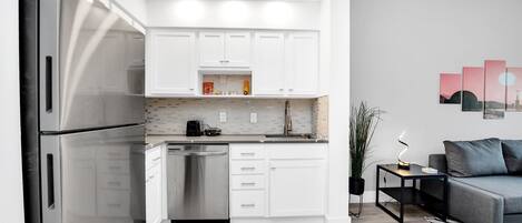 Una cocina moderna con armarios blancos, electrodomésticos de acero inoxidable y lavavajillas.