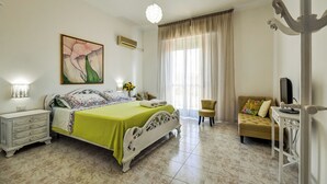 A bedroom with a bed, bedside table, lamp, and a painting on the wall. - Family run bed and breakfast. (Alghero)