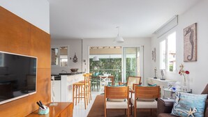 Una cocina moderna con un televisor grande, armarios de madera y un comedor con sillas y una mesa.
