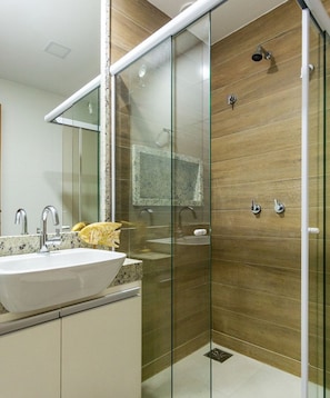 Ein modernes Badezimmer mit einer Duschkabine aus Glas, einem Waschbecken mit Granitplatte und einer Holzvertäfelung.