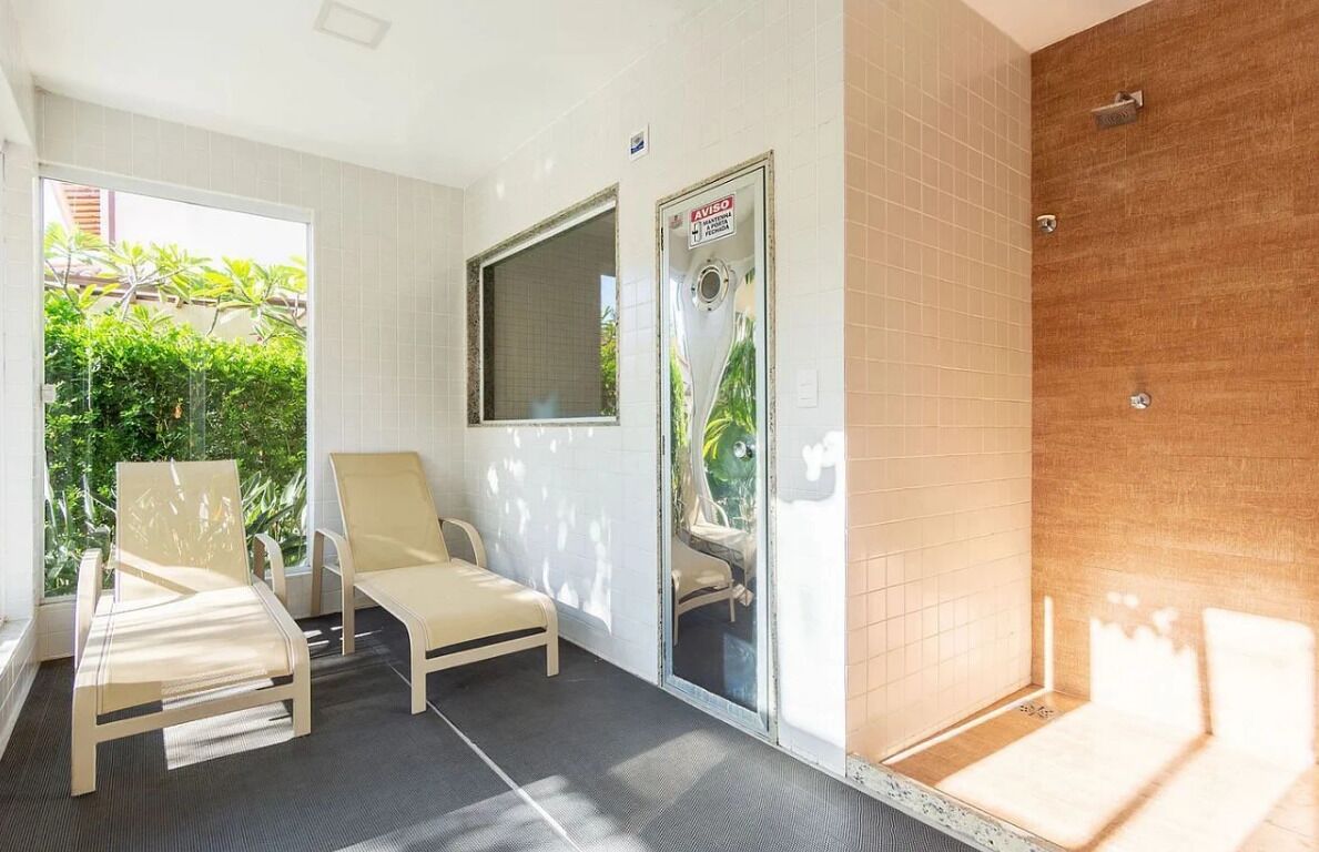 Habitación con cama, dos sillas, zona de ducha y ventana con vistas a zonas verdes.