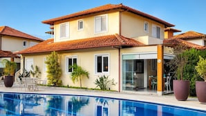 A two-story house with a swimming pool, a patio with chairs, and a door marked with the number 3A.