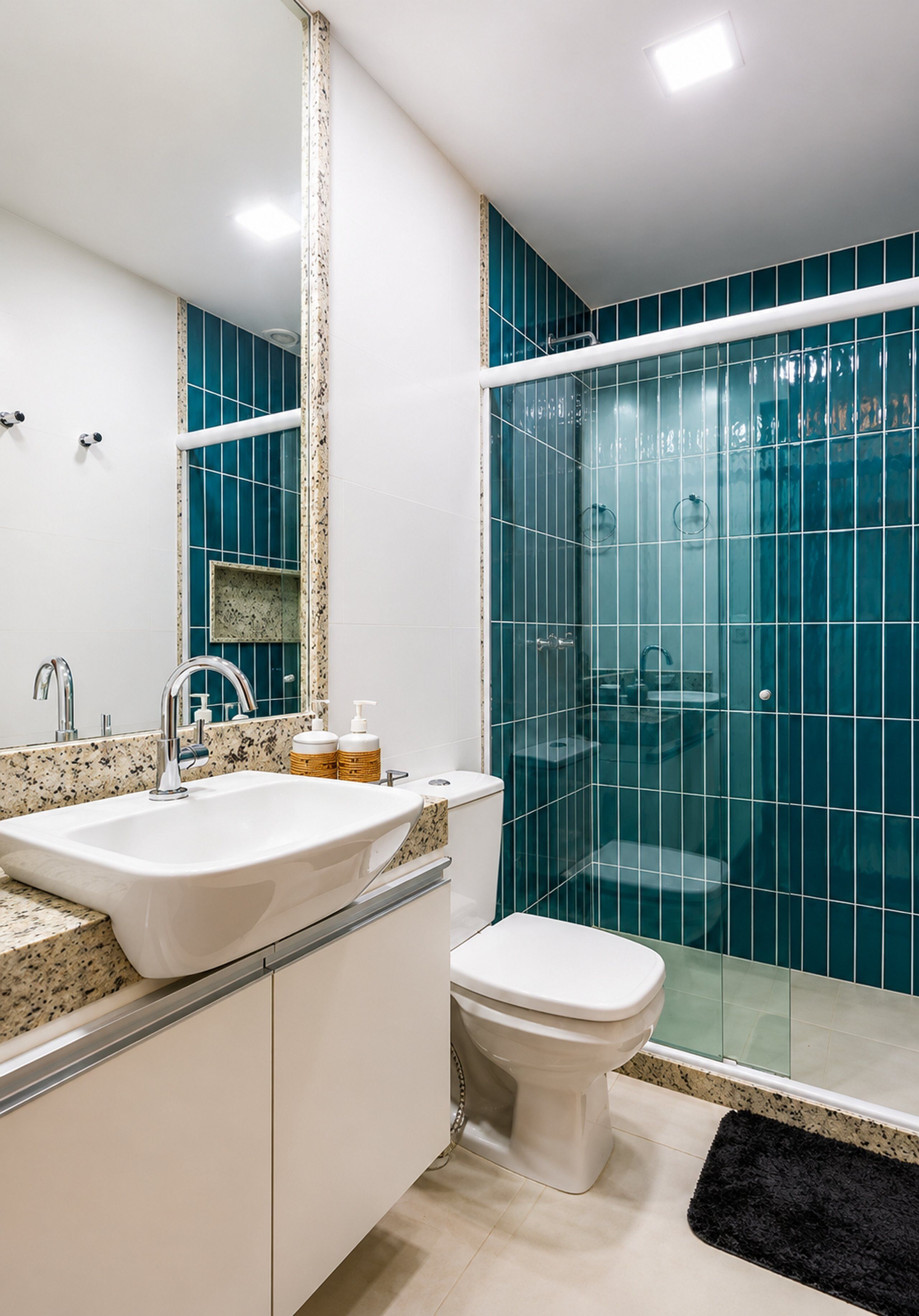 A modern bathroom with a white sink, a toilet, and a shower area with blue tiles.