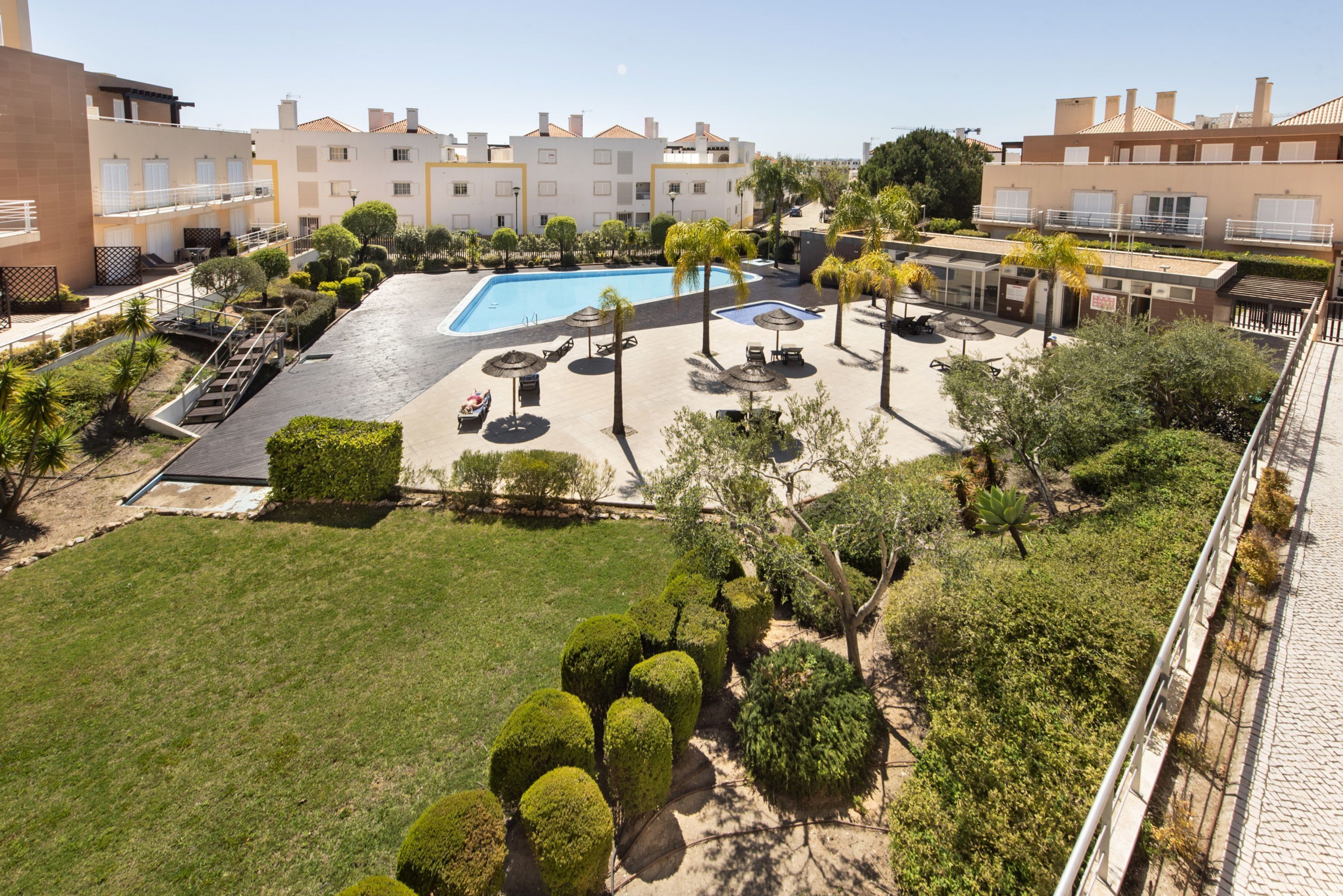 A pool area with lounge chairs, a small pool, and surrounding greenery.