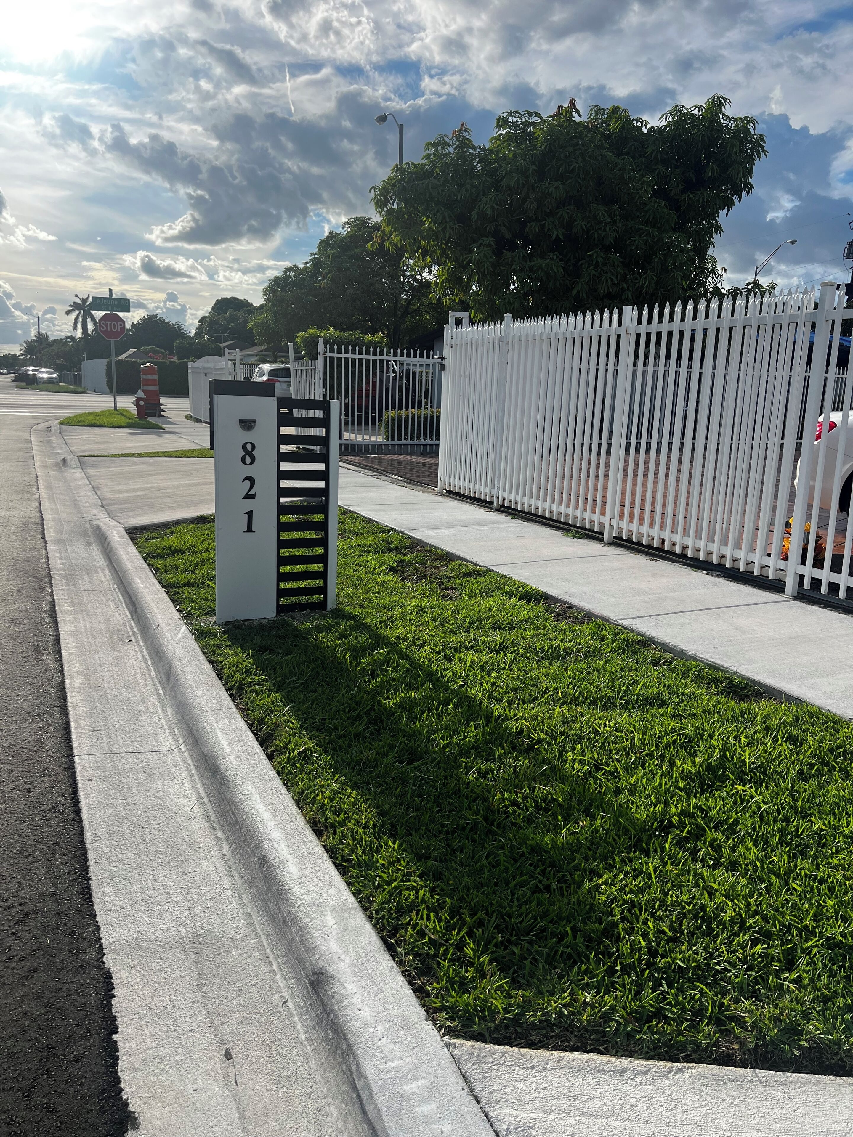 A gated residential area with a white fence, a stop sign, and a street sign indicating 'STOP'.