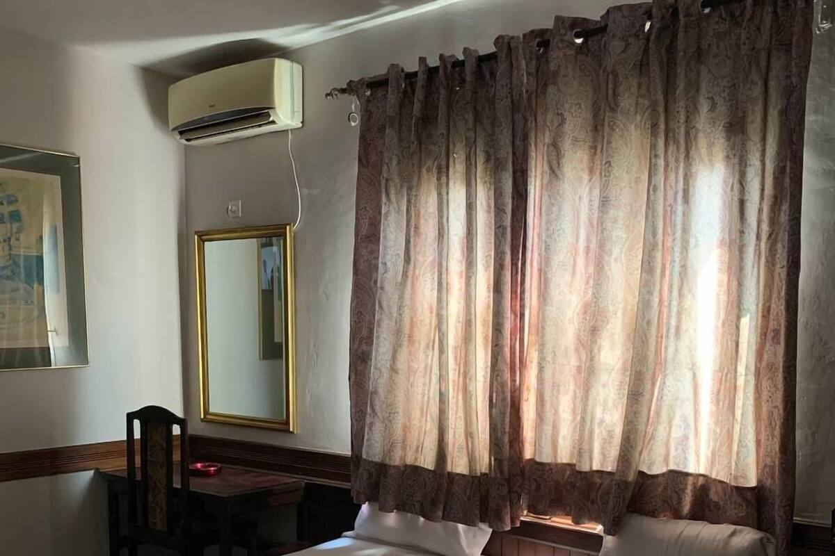 A hotel room with a bed, a desk, a chair, and a large mirror.