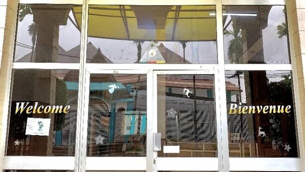 La entrada principal del Hotel Bonapriso, con una vista despejada de la recepción y un cartel de bienvenida a los huéspedes.