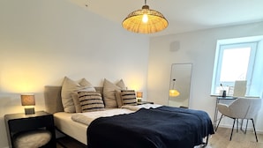 A modern bedroom with a bed, bedside tables, a large rug, and a hanging light fixture. - WeinZeit13 (Neustadt an der Weinstraße)