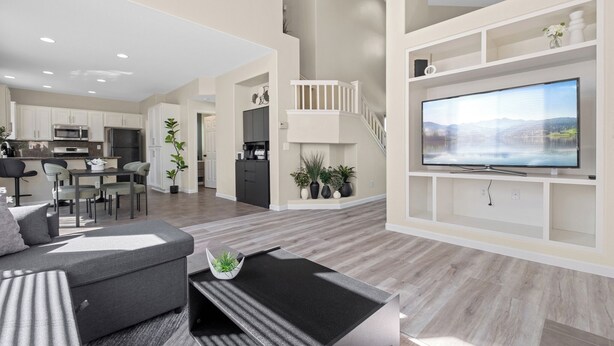 A modern living room with a large flat-screen TV, a sofa, and a coffee table. There is a kitchen area with cabinets and appliances in the background. - “NEW” Half Moon Retreat / +Pool Table / - 5 min away from GRATON casino (Santa Rosa)