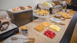 Un buffet proposant une variété de plats, notamment des pâtisseries, des fruits et un assortiment de salades.